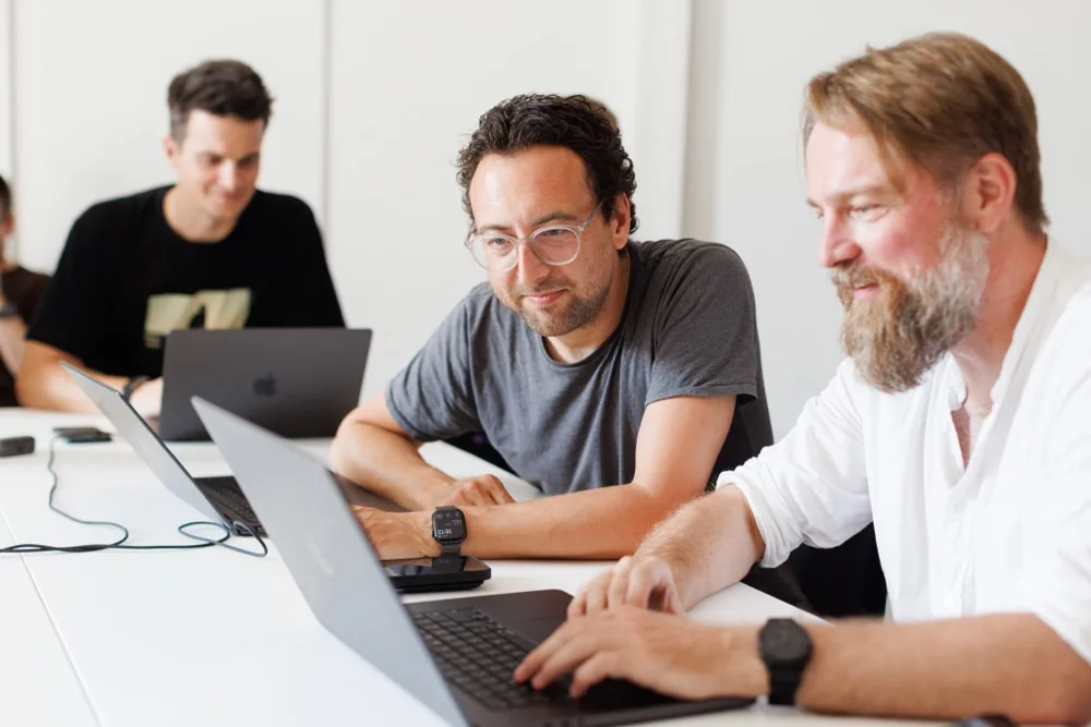 Three team members working together in front of a laptop